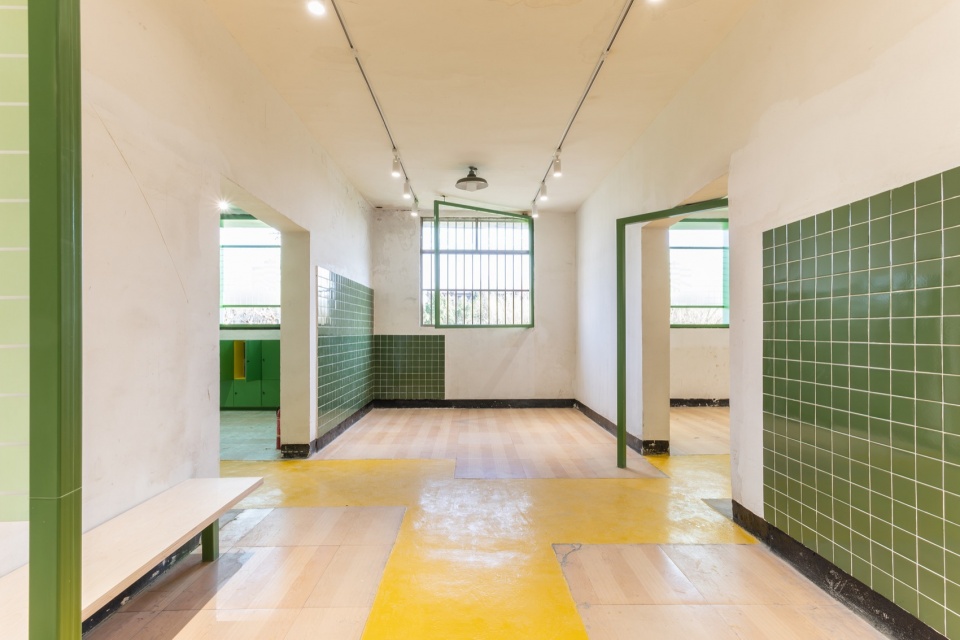 Gallery room with green tiled walls and a yellow floor path